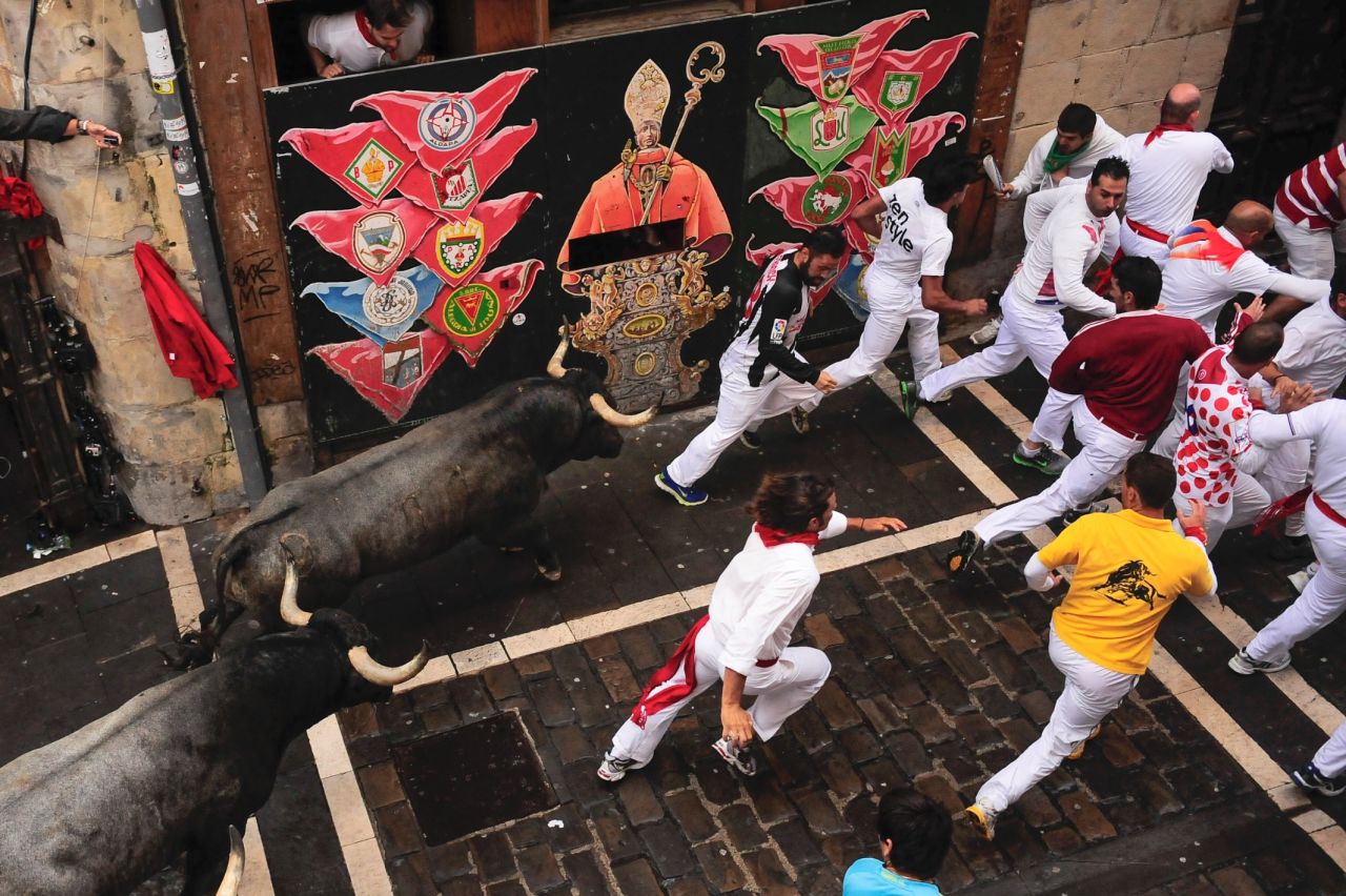 Runners pass a wall painted with an image of San Fermin, the saint the festival is named for, on July 13.