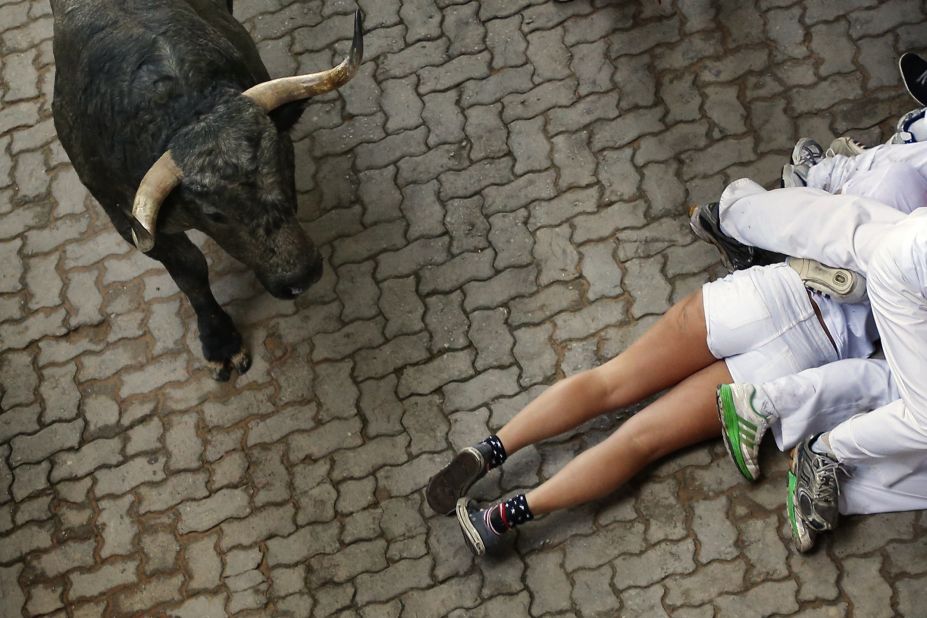 Revelers lie on the ground as a bull runs by July 13.
