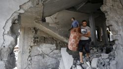 Palestinians inspect the rubble of their building that was partially destroyed following an Israeli airstrike in the morning on July 13, 2014 in Gaza City.