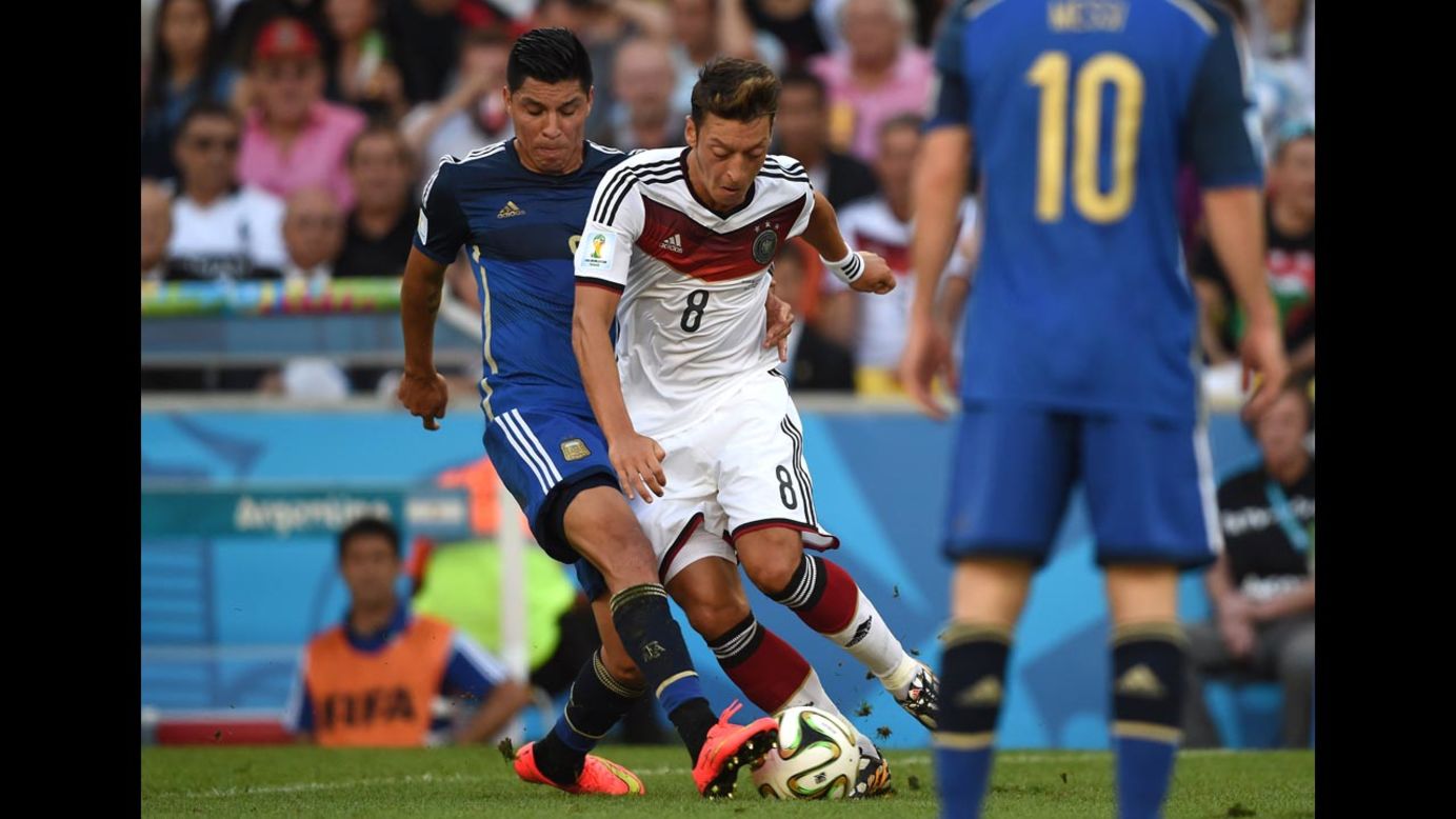 German midfielder Mesut Ozil, center, tries to dribble past Argentine midfielder Enzo Perez in the first half.