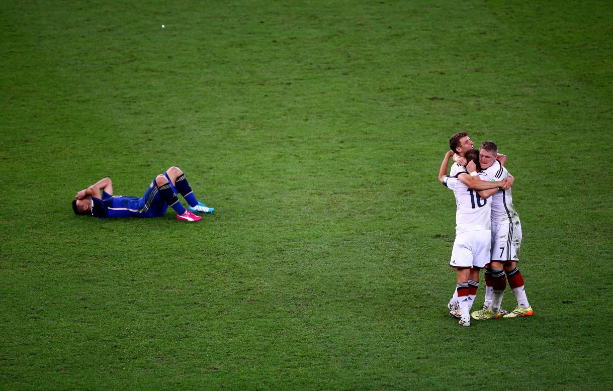 Argentina's Sergio Aguero lies on the ground as German players celebrate their victory.