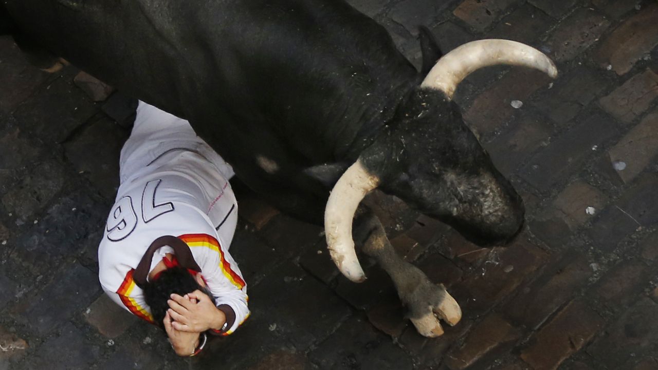 A fallen runner covers his head as a bull passes over him on July 14.