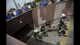 Paramedics and firefighters carry an injured man out of a subway station after a rush-hour subway train derailment in Moscow, Russia, Tuesday, July 15, 2014. A rush-hour subway train derailed in Moscow Tuesday, killing 20 people and injuring at least 150, emergency officials said. Several cars left the track in the tunnel after a power surge triggered an alarm, which caused the train to stop abruptly. (AP Photo/)
