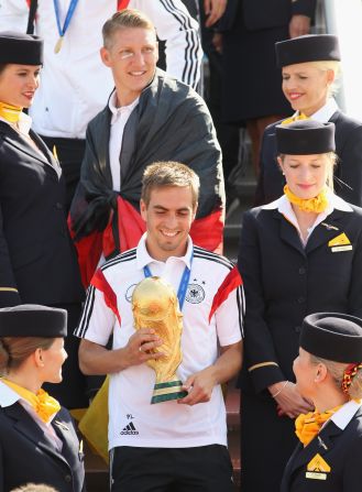 Germany captain Philipp Lahm carries some very special cargo off the plane -- the Jules Rimet Trophy -- as the team land on home soil.