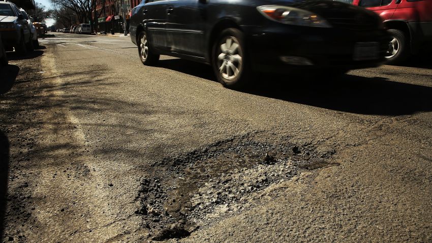 A car travels past a pothole in Brooklyn, New York. After a severe winter, New York City's streets have become treacherous in areas