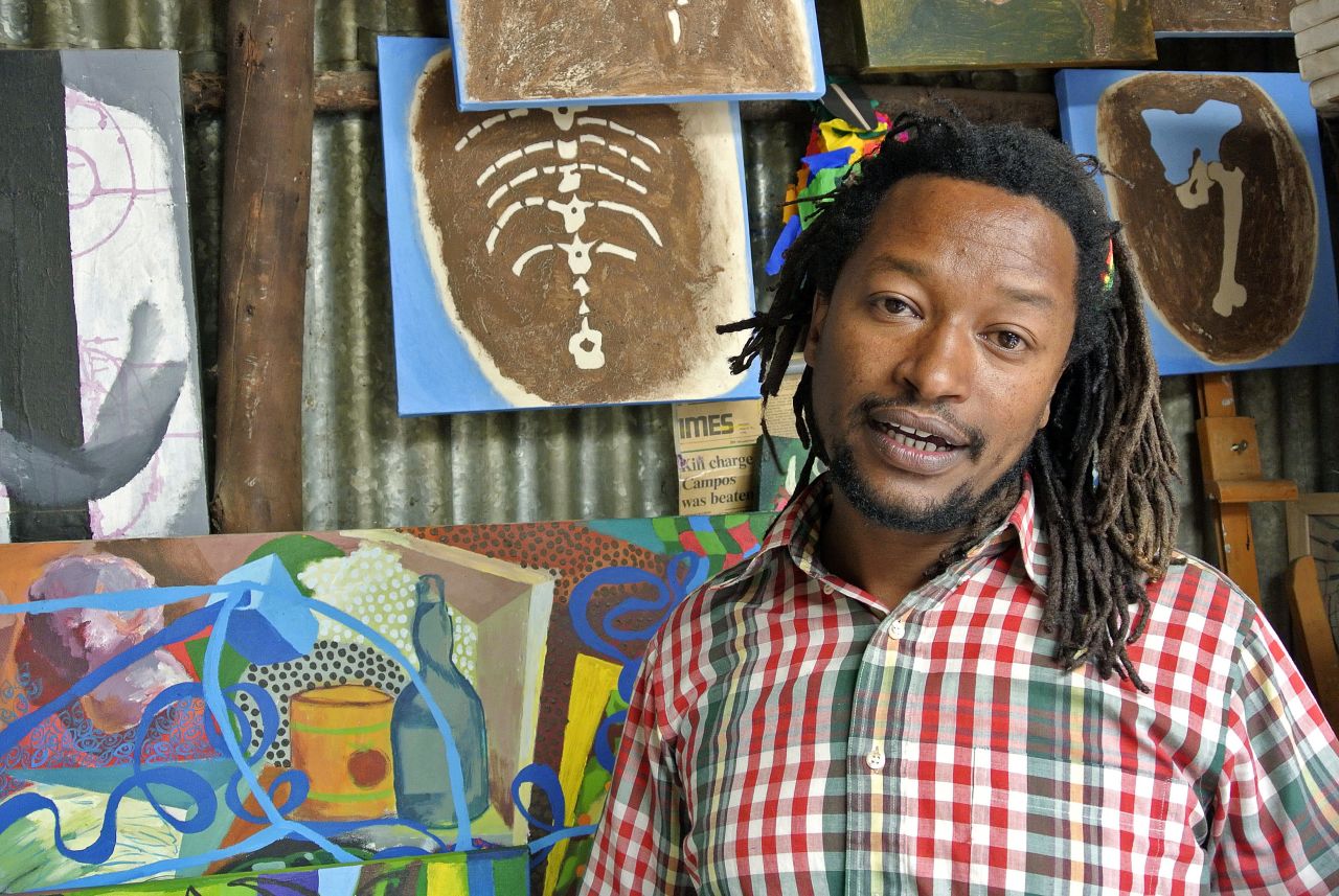 Contemporary Ethiopian artist Tamrat Gezahegn poses with some of his paintings at the Netsa Art Village in Addis Ababa, Ethiopia.