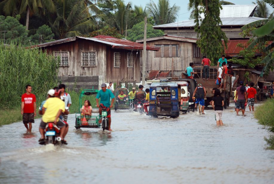 Residents cross a flooded road on July 15 in Sultan Kudarat, Mindanao, Philippines. Mudslides and flooding are feared across the country.