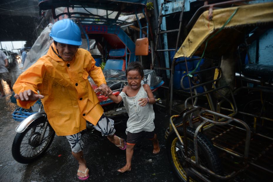 A village official leads a child as he is evacuated from their house at an informal settlers' area as Typhoon Rammasun lashes rain on Manila on July 16, 2014. 