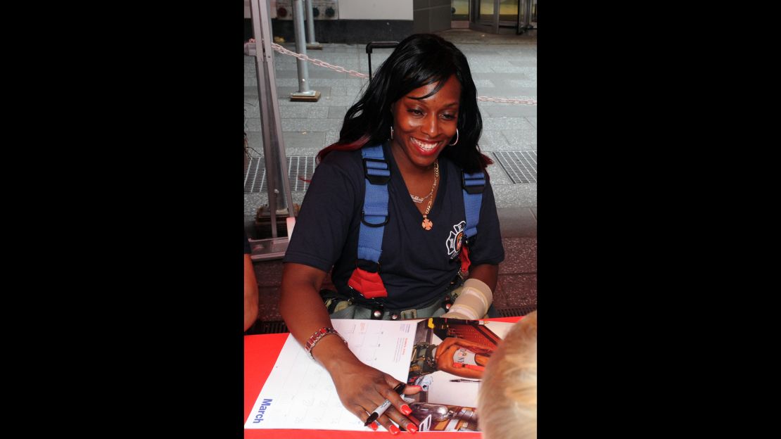 Danae Mines signs a copy of the 2015 FDNY Calendar of Heroes.