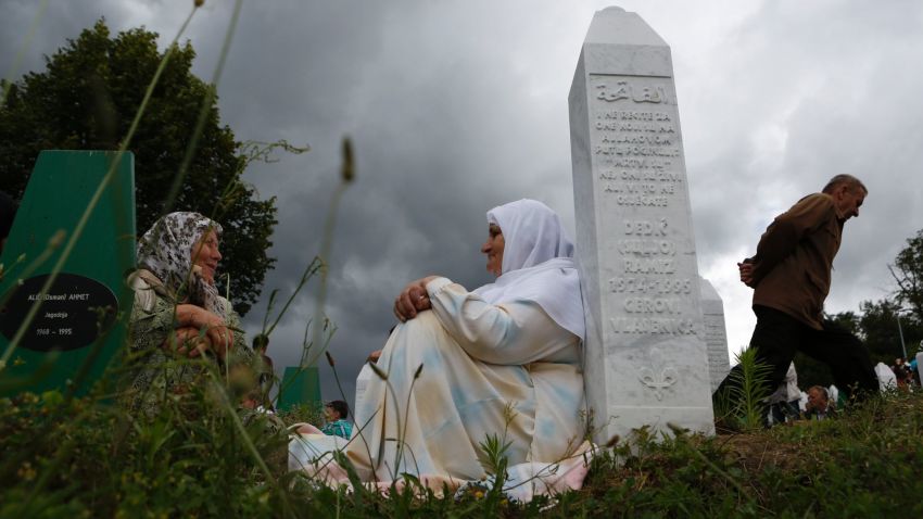 Bosnian Muslim women rest near a gravestone during a funeral in Srebrenica, Bosnia on Friday July 11, 2014. T