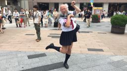Hideaki Kobayashi, 51, strikes his signature "cat" pose outside Akihabara station in Tokyo on Sunday July 13.  Underneath the Japanese schoolgirl facade, he is a patent-holding computer engineer and accomplished photographer.