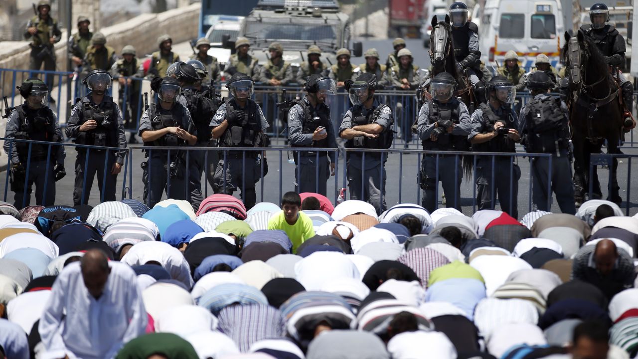 Israeli police stand guard as Muslim men pray in the street outside the Old City in East Jerusalem on July 4.