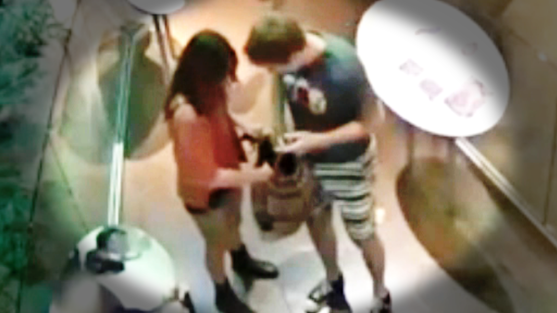 A surveillance image shows a male putting something into a large, multicolored bag carried by a female accomplice.