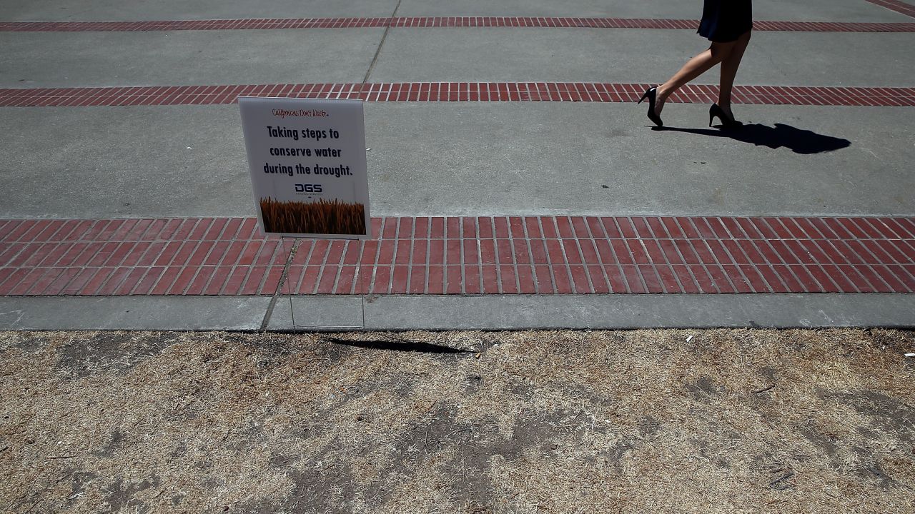 In June 2014, a pedestrian walks by a sign posted in front of the lawn at the California State Capitol in Sacramento.