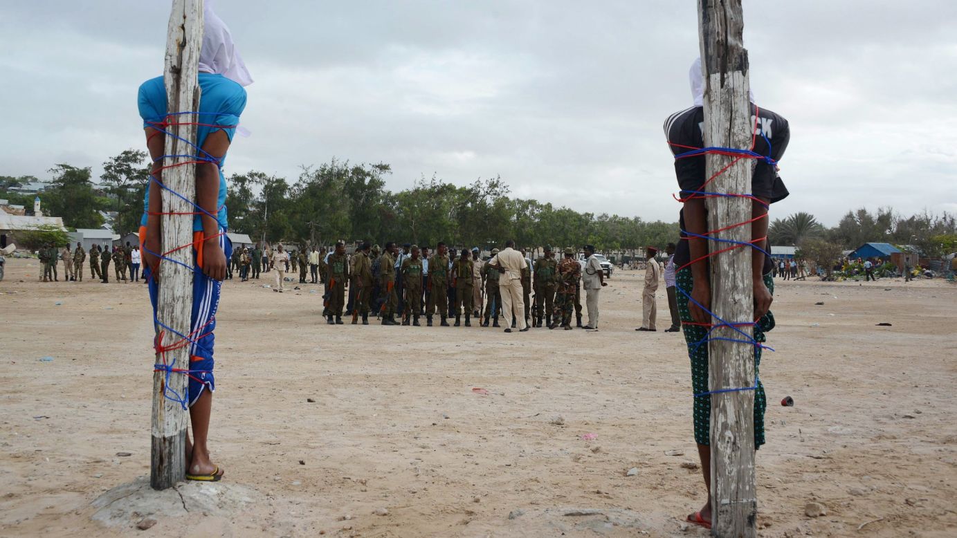 Two Somalis tied to large wooden stakes wait to be executed by a firing squad on Tuesday, July 15, in Mogadishu. They were convicted of murdering a Somali nurse working with a Turkish medical unit.