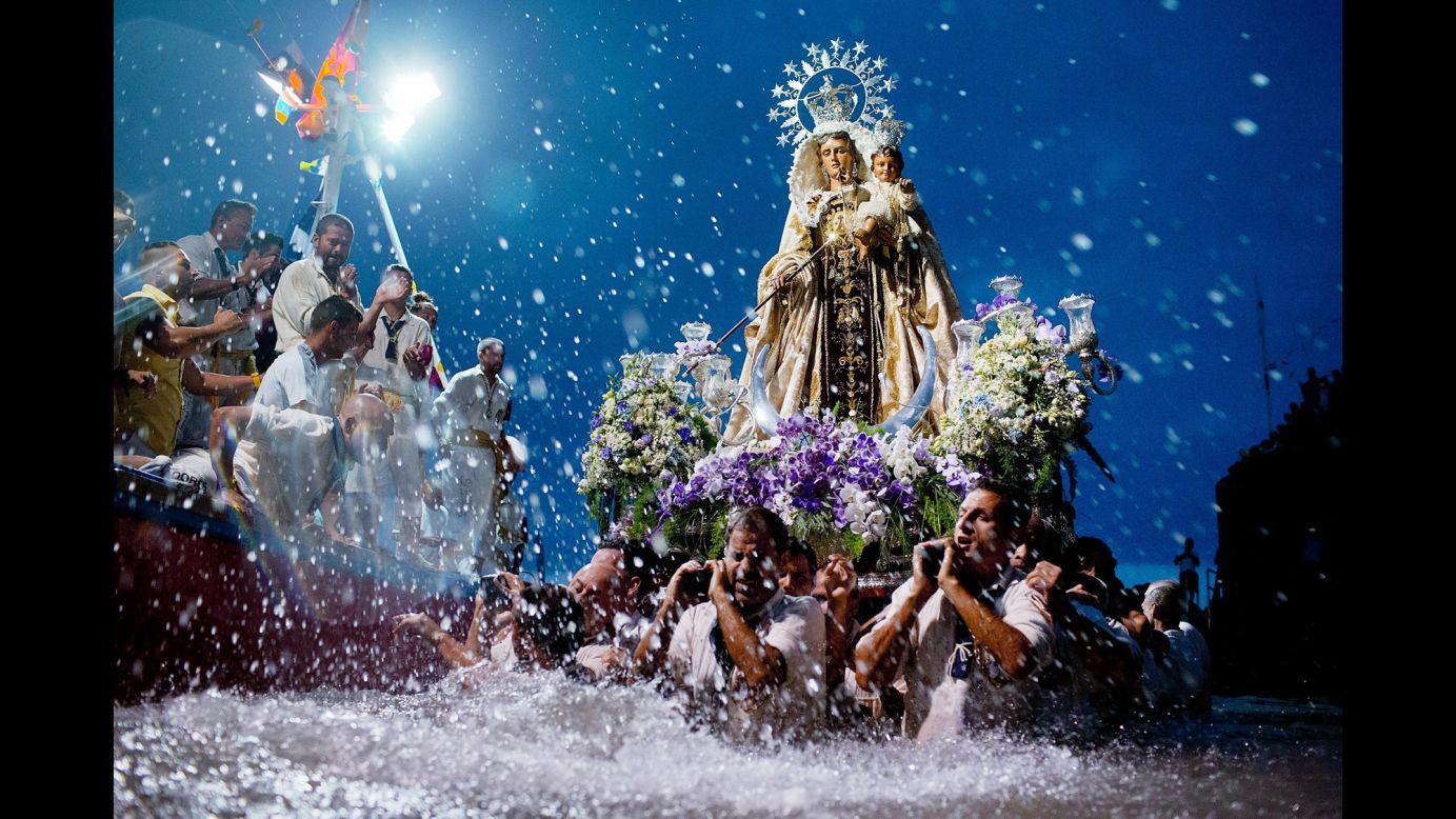 Carriers of the Great God Power brotherhood unload a Virgen del Carmen statue at the Puerto de la Cruz dock on the Canary island of Tenerife, Spain, on Tuesday, July 15. The procession with the statue of the patron saint of fisherman has taken place since 1921.