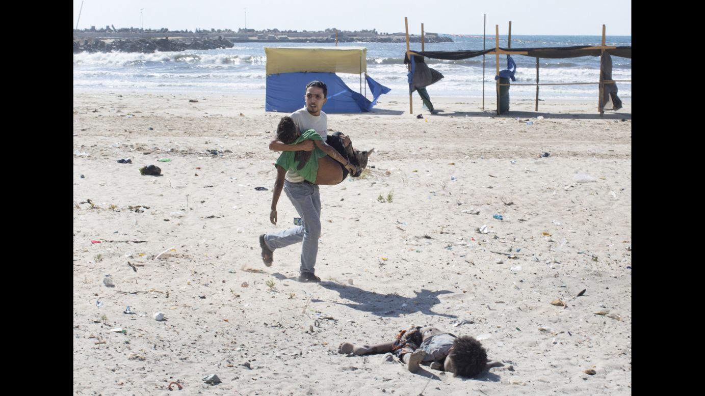 A Palestinian man carries a child as another lies dead on a beach in Gaza City on Wednesday, July 16. Shells fired by an Israeli gunboat <a href="http://www.cnn.com/2014/07/17/world/meast/mideast-conflict-children/index.html" target="_blank">killed four boys</a> between ages 9 and 11, officials said. The Israeli military said the intended target was likely "Hamas terrorist operatives."