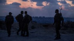 Israeli soldiers stand near the southern Israeli border with the Gaza Strip (background) on July 17, 2014.