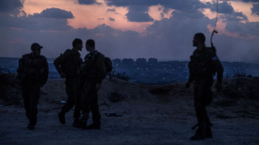 Israeli soldiers stand near the southern Israeli border with the Gaza Strip (background) on July 17, 2014.