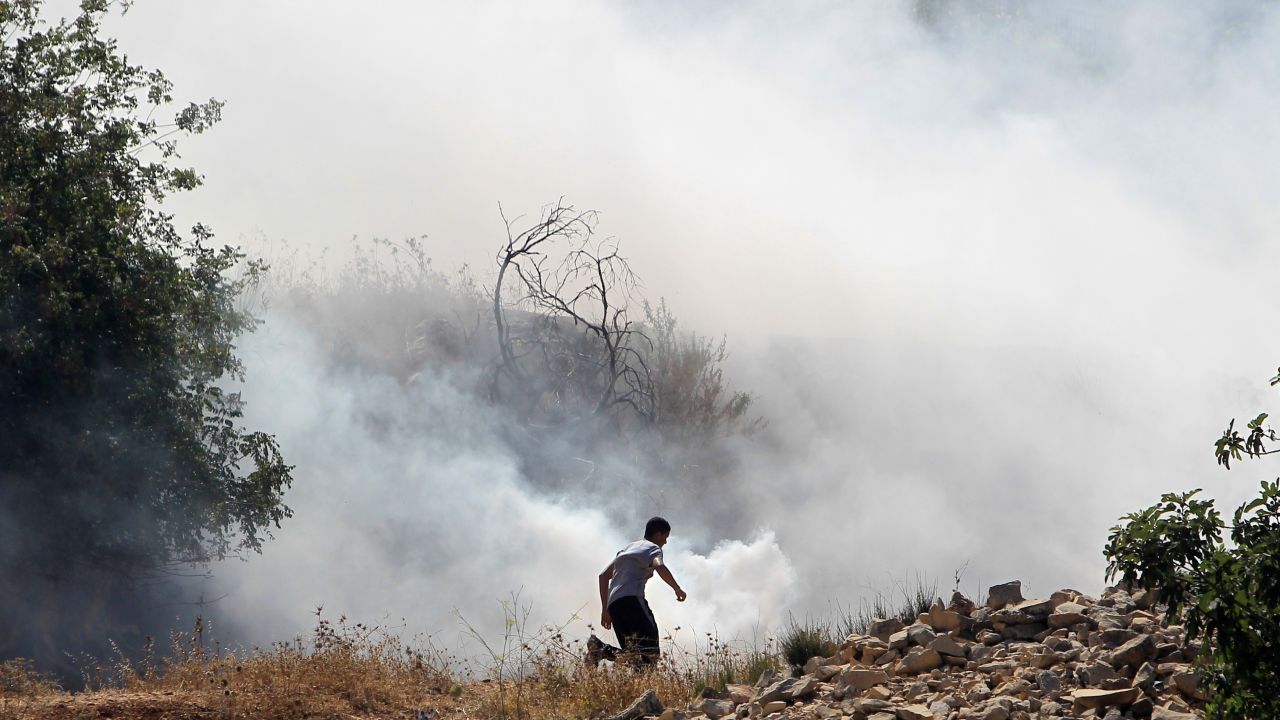 A Palestinian demonstrator, protesting Israel's military operation in Gaza, runs through smoke July 18 during clashes with Israeli soldiers at the entrance of the Ofer prison in the West Bank village of Betunia.