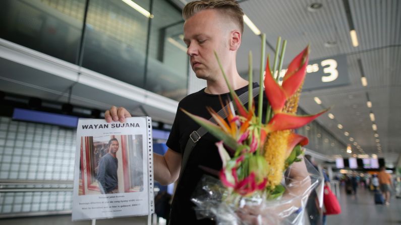 Arthur Laumann holds a floral tribute and photograph of family friend Wayan Sujana, believed to be missing on the flight, at Schiphol Airport on July 18 in Amsterdam.