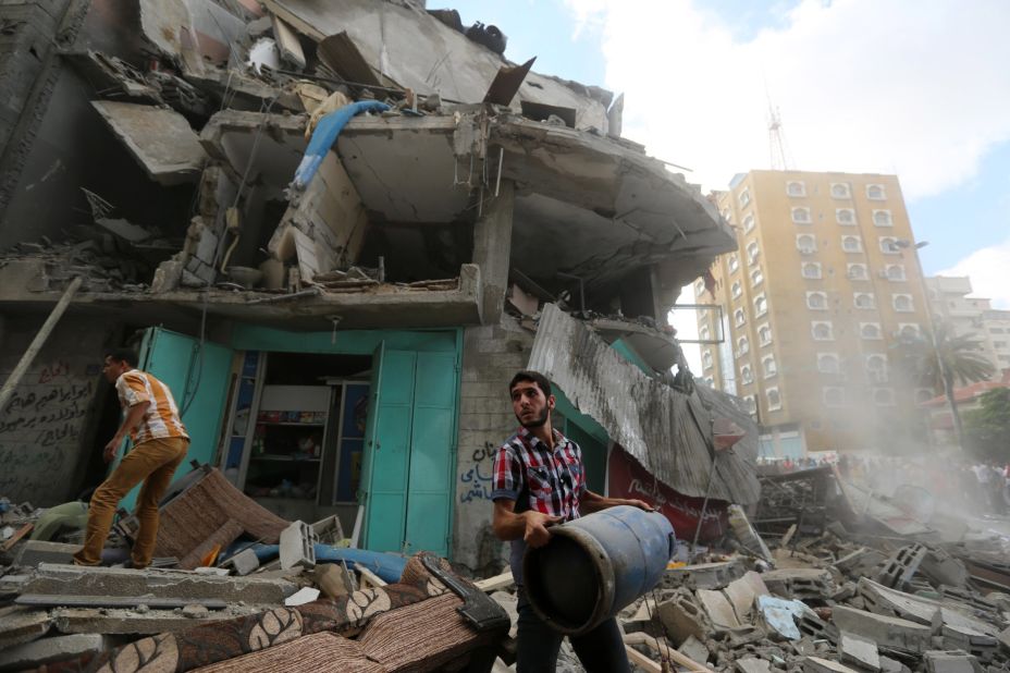 A Palestinian carries a gas cylinder salvaged from the rubble of an apartment building after it was hit by Israeli fire on July 18.