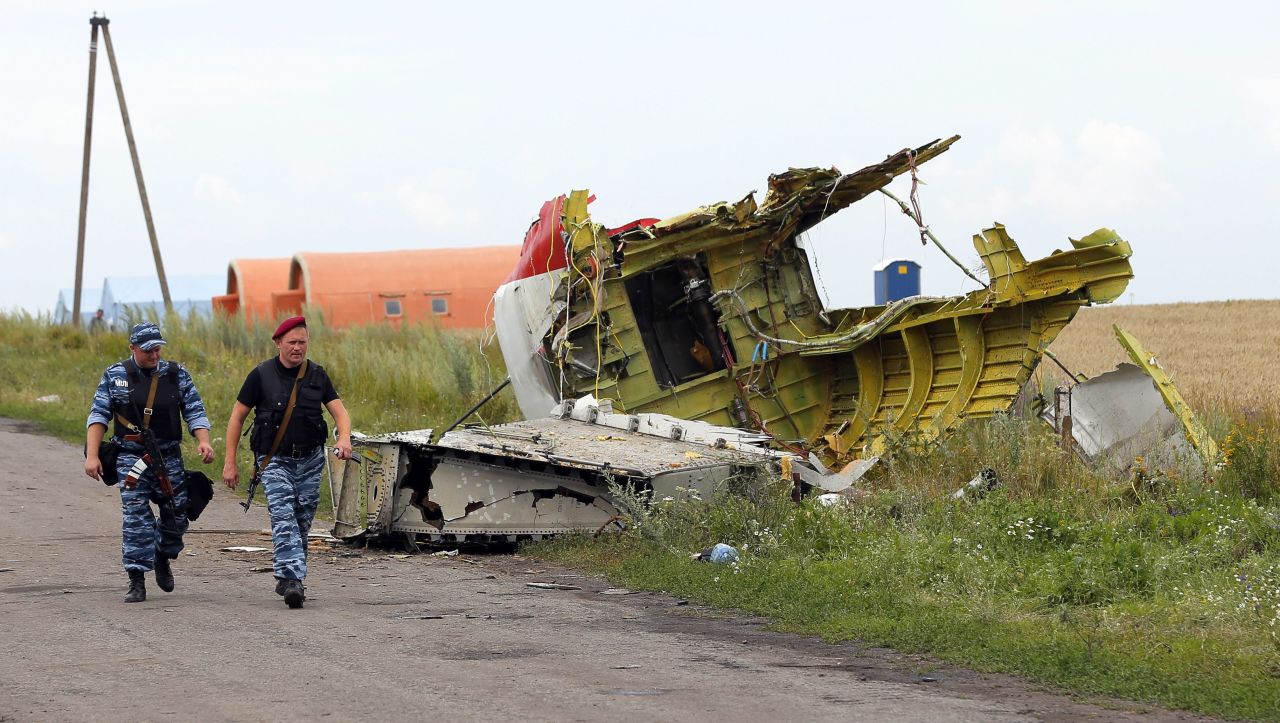 Armed rebels walk past large pieces of the Boeing 777 on July 19, 2014. 