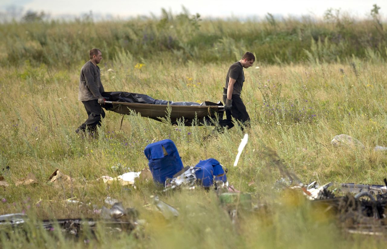 Emergency workers carry the body of a victim at the crash site on July 19, 2014. 