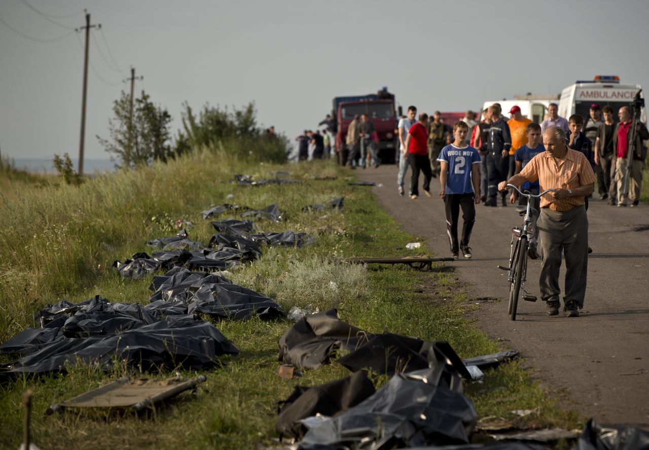 Victims' bodies are placed by the side of the road on July 19, 2014, as recovery efforts continue at the crash site. International officials lament the lack of a secured perimeter.
