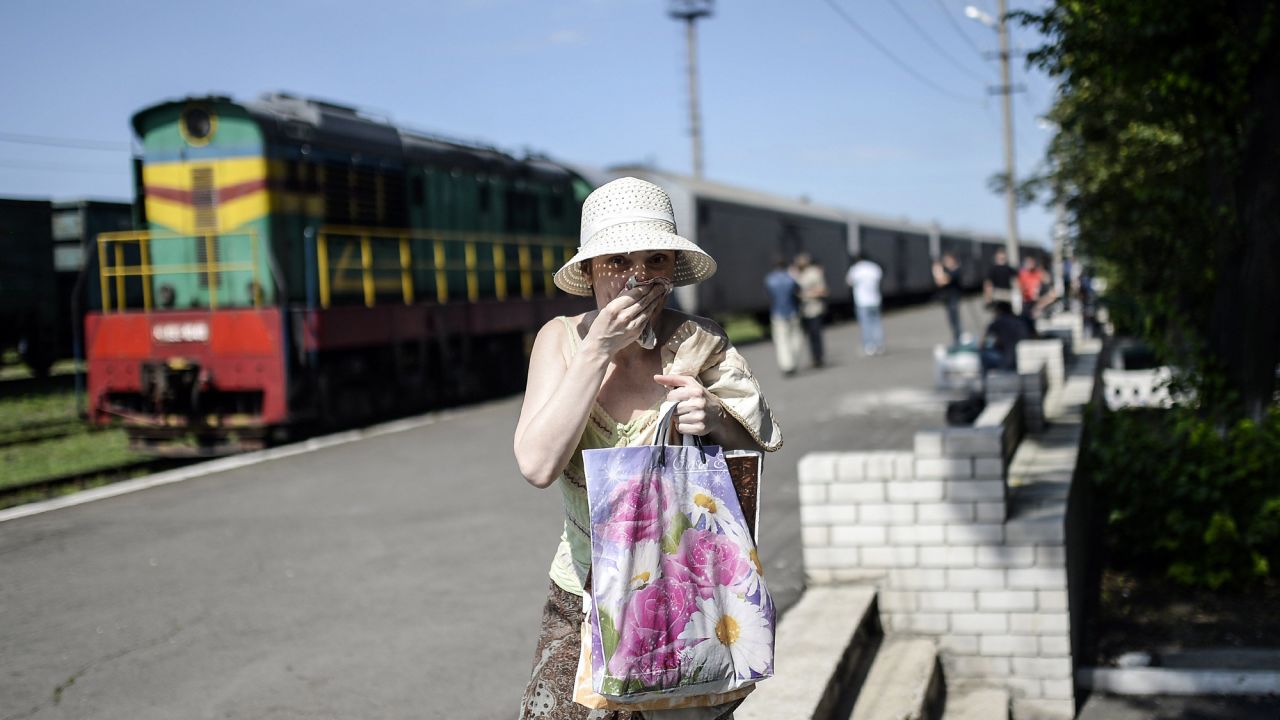 A woman covers her mouth with a piece of fabric July 20, 2014, to ward off smells from railway cars that reportedly contained passengers' bodies.
