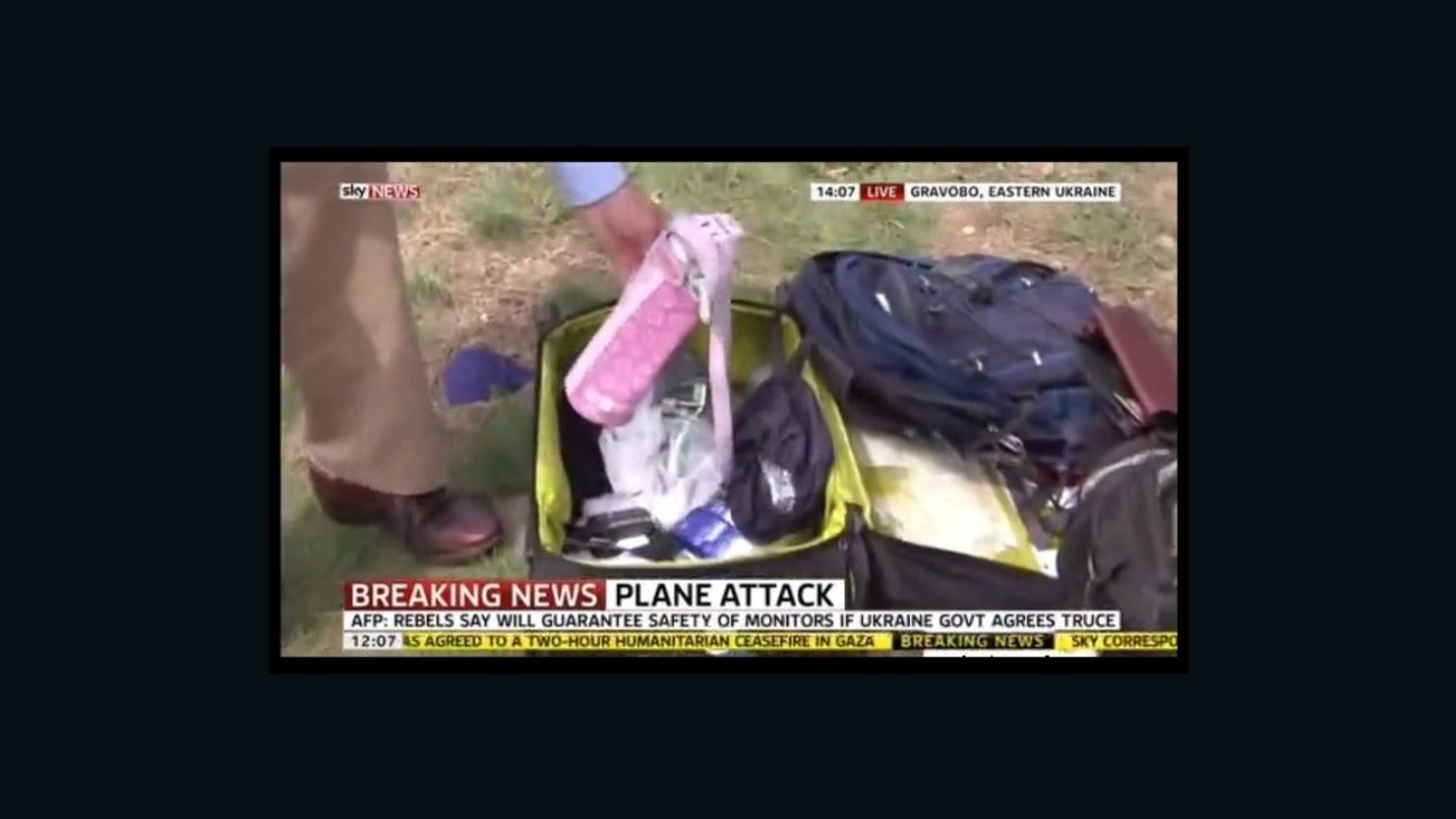 A reporter picks up the belongings of MH17 victims during a live Sky News broadcast at the crash site in eastern Ukraine.