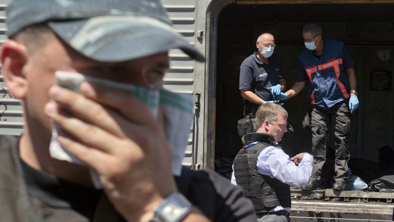 A man covers his face with a rag as members of the Organization for Security and Co-operation in Europe and the Dutch National Forensic Investigations Team inspect bodies in a refrigerated train near the crash site in eastern Ukraine on July 21, 2014.