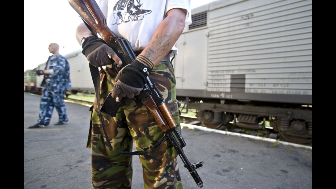 An armed pro-Russian rebel stands guard next to a refrigerated train loaded with bodies in Torez, Ukraine, on Sunday, July 20, 2014.