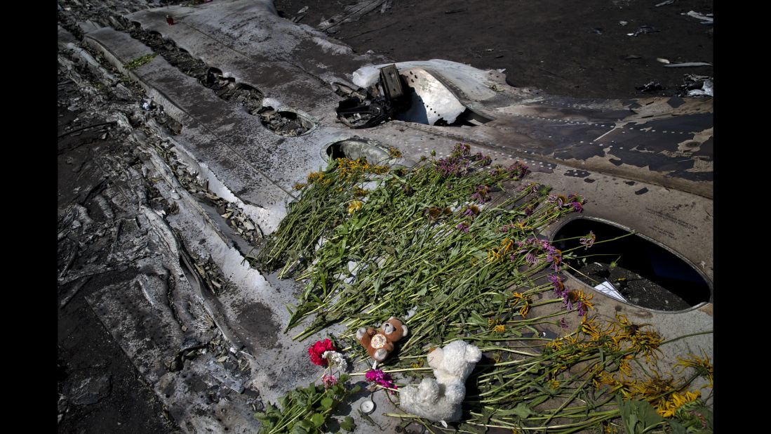 Toys and flowers sit on the charred fuselage of the jet as a memorial on July 20, 2014.