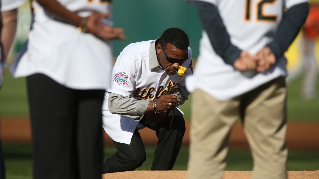 Baseball Hall of Famer Rickey Henderson carries a rose to the pitcher's mound on Saturday, July 19, as he and other members of the 1989 Oakland Athletics team celebrated the 25th anniversary of their World Series win. Henderson laid the rose at the mound in honor of former teammate Bob Welch, who died last month.