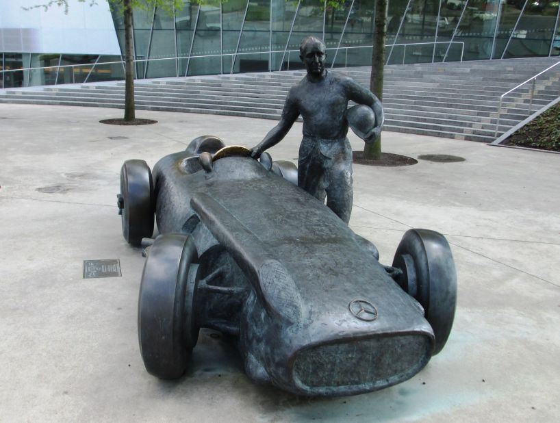 Outside the Mercedes museum, a bronze statue depicts five-time world champion F1 driver Juan Manuel Fangio standing next to his 1954 W196 grand prix racer.