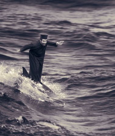 Fontcuberta satiriza la fe religiosa en esta imagen, "El milagro del surf sobre un delfín", en la que él mismo aparece como un moje que hace milagros. 