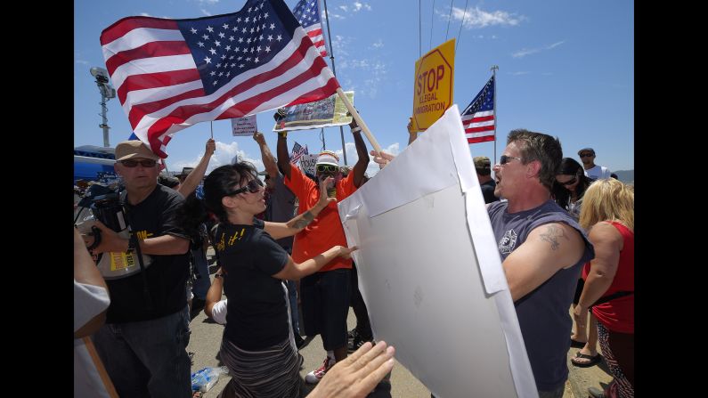 Demonstrators from opposing sides of the immigration issue confront each other outside a U.S. Border Patrol station in Murrieta, California, on Friday, July 4. Some activists are demanding immediate deportation. Others say the migrants are only fleeing violence at home.