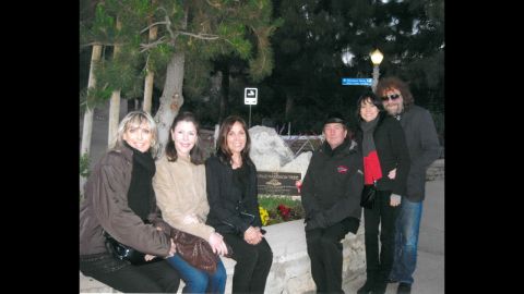 The George Harrison tree in LA's Griffith Park is behind family and friends including Harrison's widow, Olivia (center, in black), Eric Idle of Monty Python fame near her, and Jeff Lynne (far right) of ELO and Harrison's band The Travelling Wilburys. The tree was killed by an infestation of beetles.