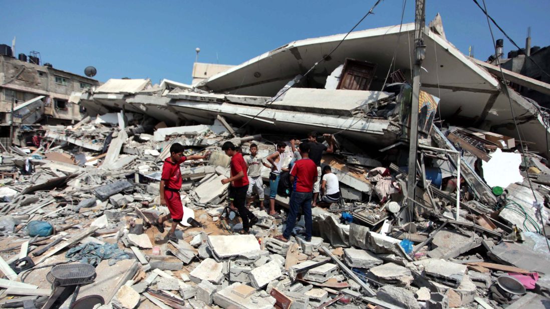 Palestinians inspect destroyed buildings and collect usable items after an Israeli air assault on July 22.
