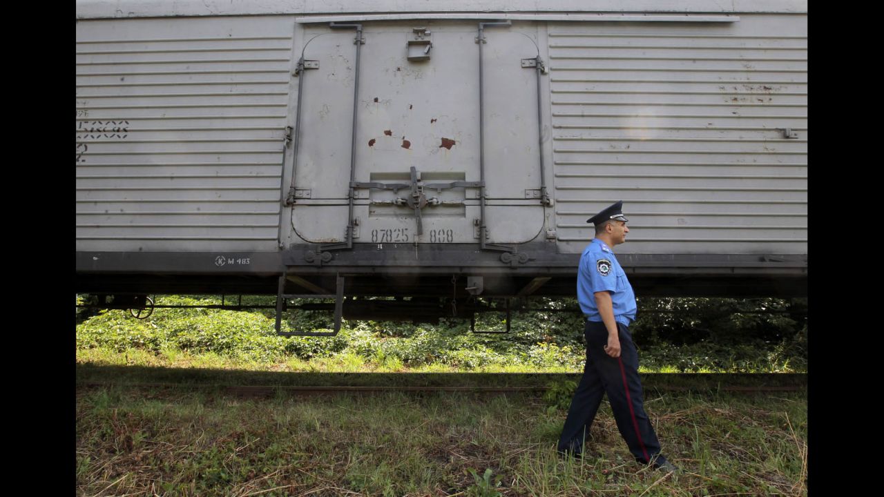 A police officer in Kharkiv walks past a refrigerated container car loaded with bodies on July 22.