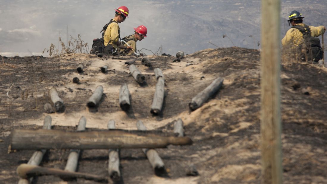 Firefighters work in a field near a burnt fence Sunday, July 20, near Brewster, Washington. <a href="http://www.cnn.com/2014/07/20/us/pacific-northwest-wildfires/index.html">Nearly a million acres</a> were burning Sunday as 21 wildfires raged in the Pacific Northwest, fire officials said.