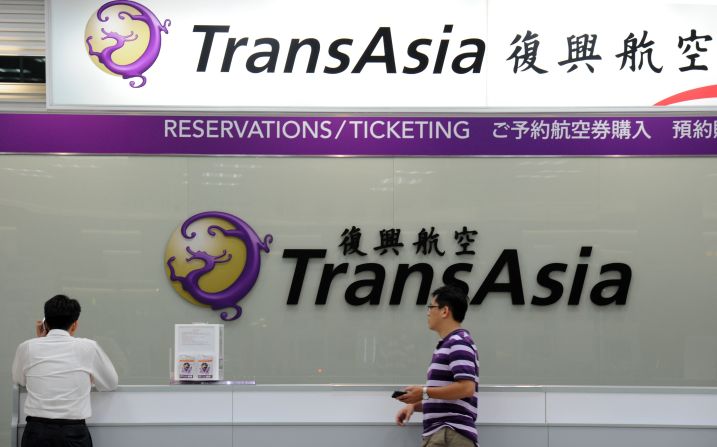 Local journalists wait in front of a TransAsia reservations desk at the Taipei Sungshan Airport in Taipei, Taiwan, on July 23.