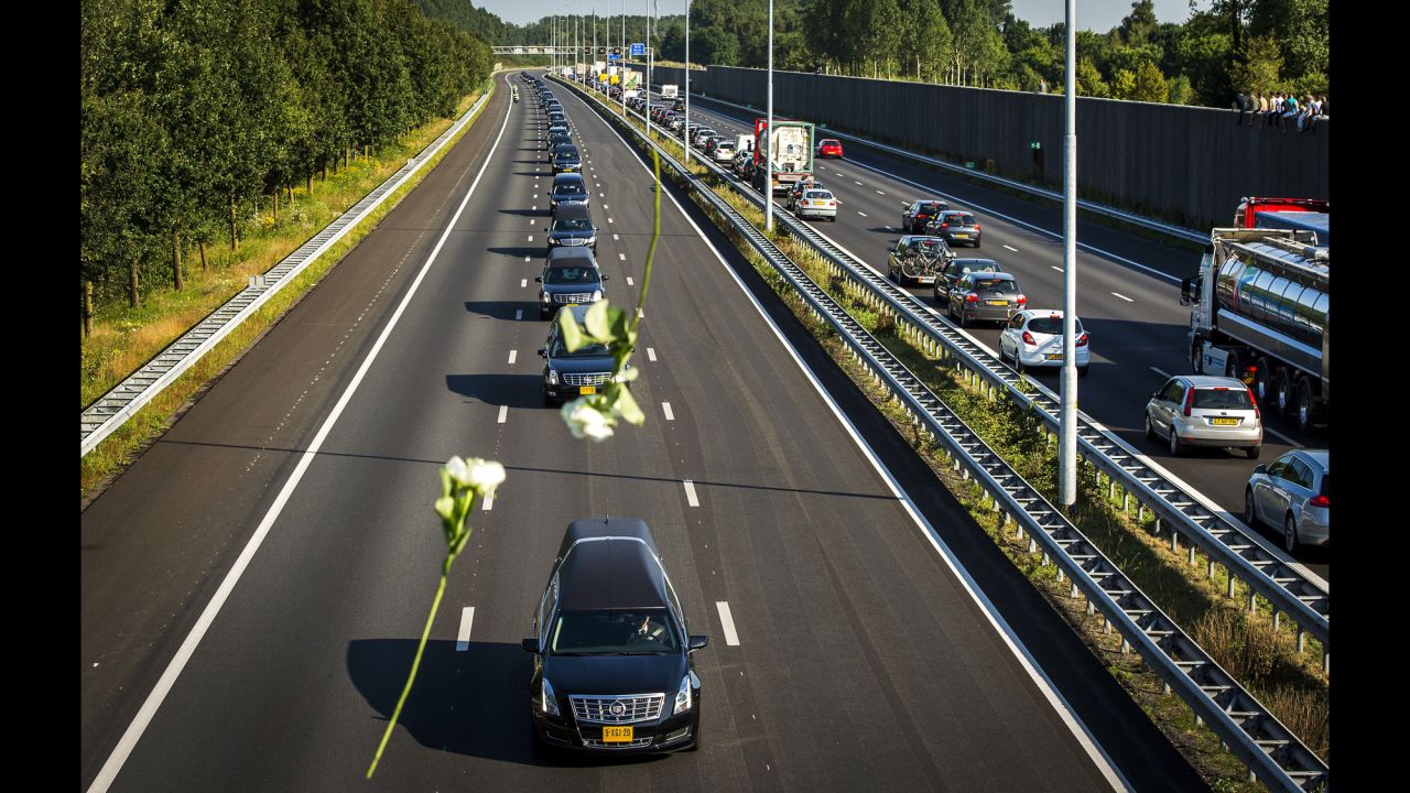 Flowers are thrown from a bridge Wednesday, July 23, as hearses carry victims to Hilversum.