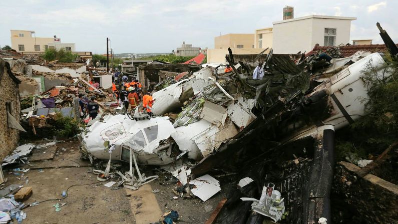 Rescue workers survey the wreckage of the flight on Thursday, July 24. The plane was attempting to land in stormy weather but crashed on the island late Wednesday, wrecking houses and cars on the ground. 