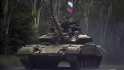 Pro-Russian rebels ride on a tank flying Russia's flag, on a road east of Donetsk, Monday, July 21, 2014. Another 21 bodies have been found in the sprawling fields of east Ukraine where Malaysia Airlines Flight 17 was downed last week, killing all 298 people aboard. International indignation over the incident has grown as investigators still only have limited access to the crash site and it remains unclear when and where the victims' bodies will be transported. (AP Photo/Vadim Ghirda)