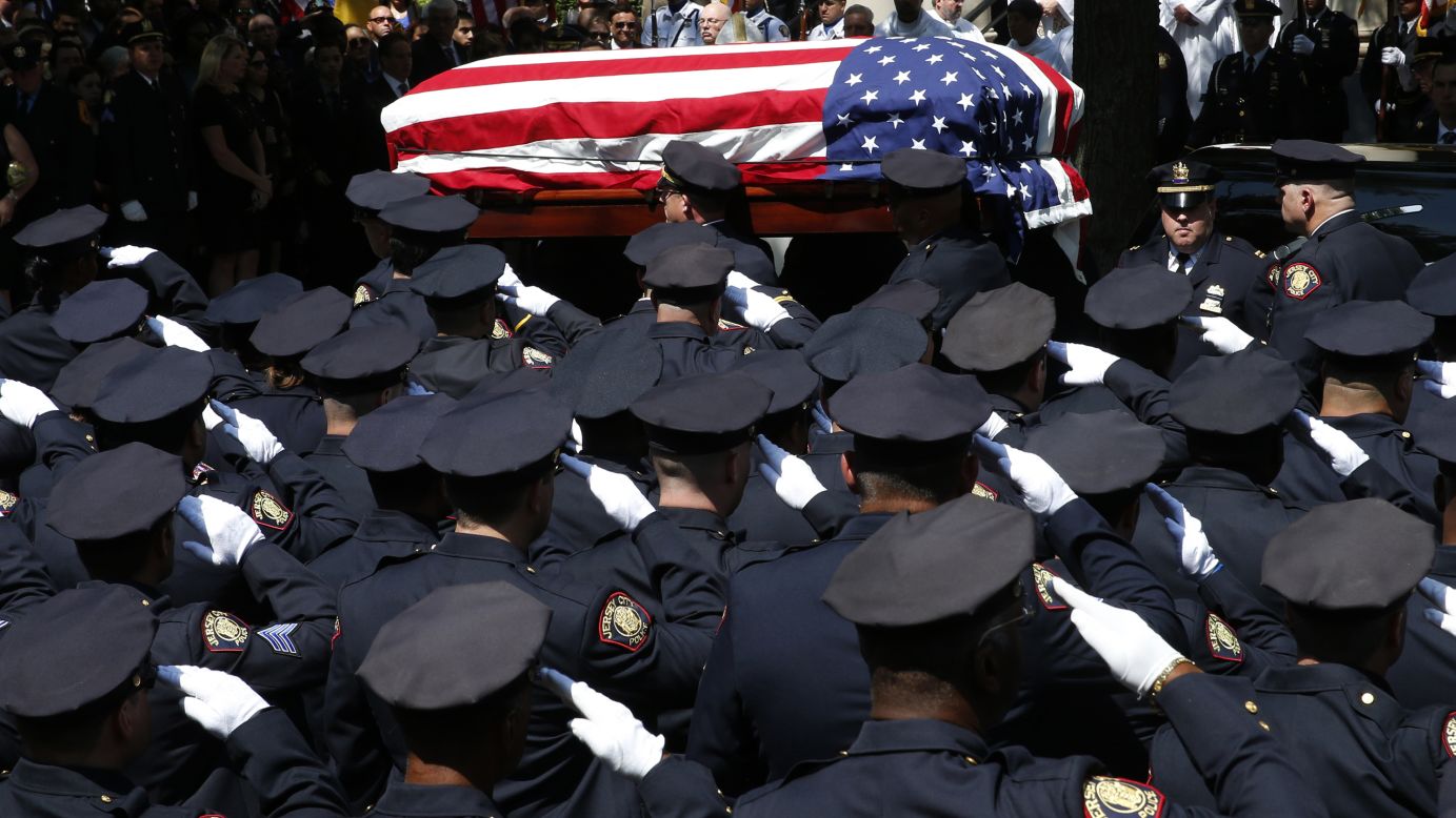 Police officers salute as the casket carrying slain police officer Melvin Santiago is carried into a church for his funeral service in Jersey City, New Jersey, on Friday, July 18. Santiago was shot and killed in his car after responding to an armed robbery call, officials said.