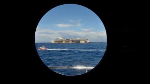 A view from a porthole shows the wreck of the Costa Concordia as it's being towed on July 23. It'll take about two years to dismantle the massive cruise liner.<br />