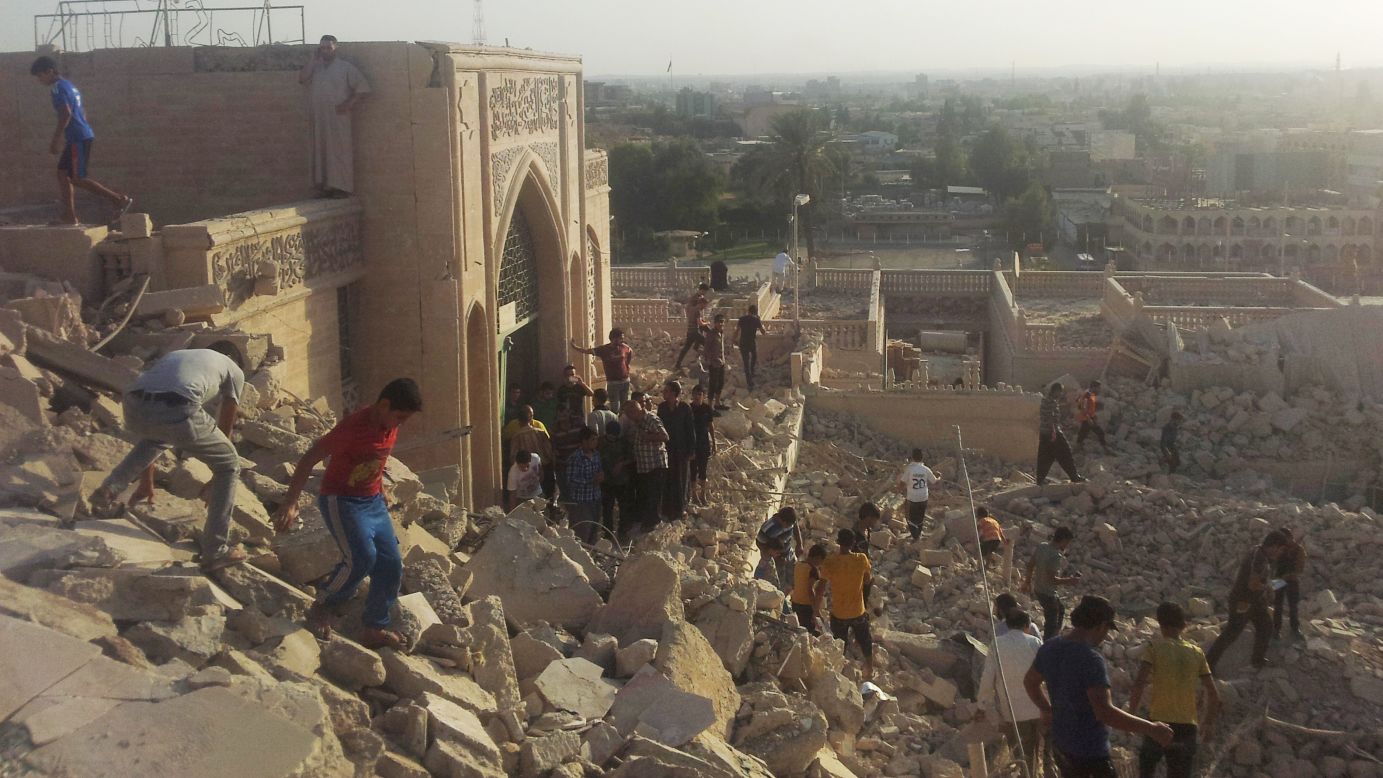 People walk on the rubble of the destroyed Mosque of the Prophet Yunis (Arabic for Jonah) in Mosul, Iraq, on Thursday, July 24. Militants belonging to the Islamic State in Iraq and Syria, or ISIS, planted explosives around the tomb and detonated the explosion remotely, civil defense officials told CNN.