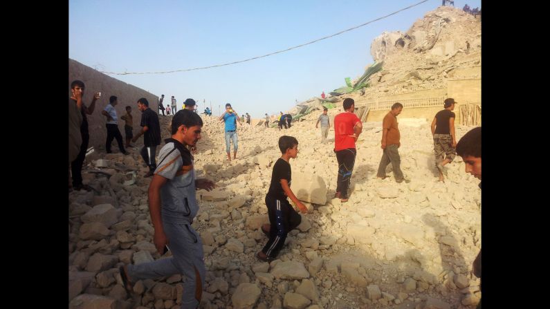 Iraqis walk on the rubble of what was once the tomb of the prophet Jonah, who famously survived three days in the belly of a whale.